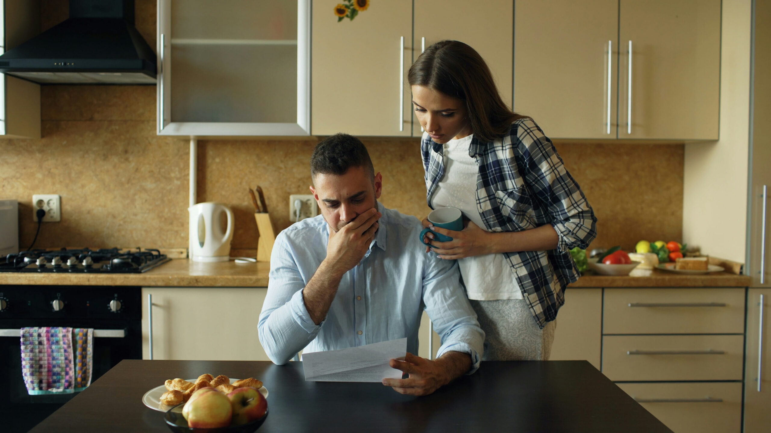Taxpayer reviewing IRS bills at kitchen table representing financial hardship and need for tax relief options
